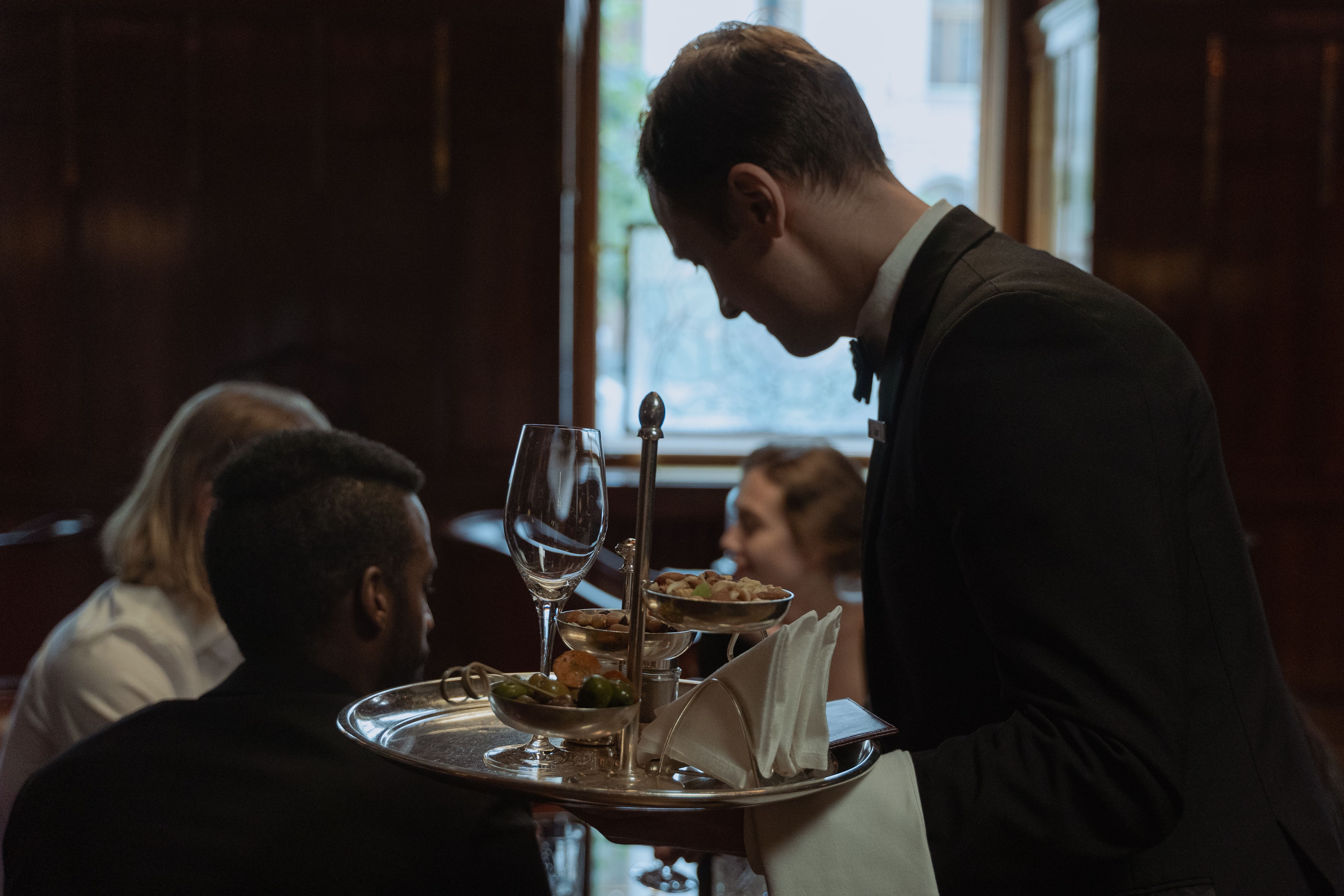 Waiter serving a group of adults enjoying a fine dining experience in an elegant restaurant