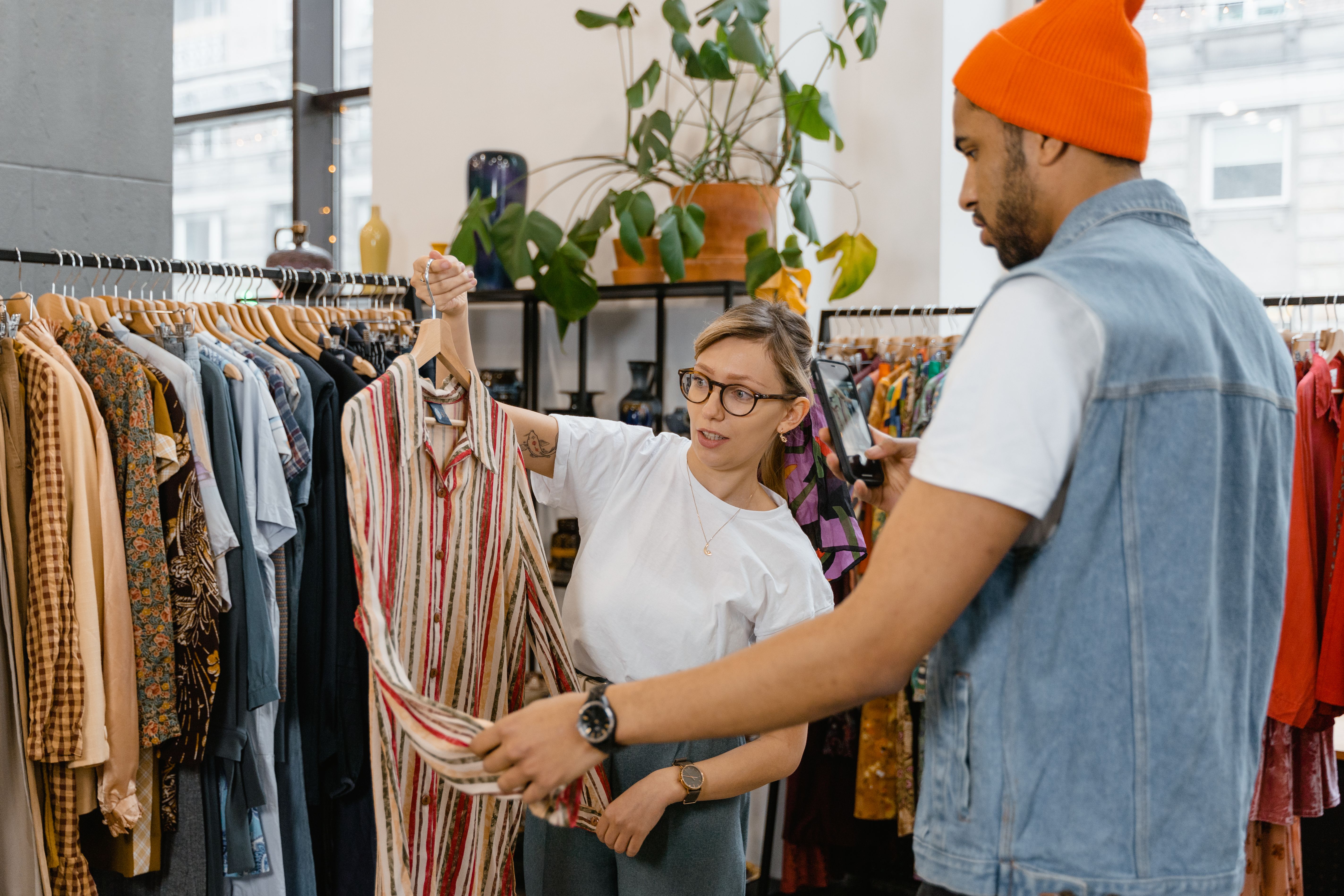 Store assistant helping a customer choose a shirt in a modern clothing retail store